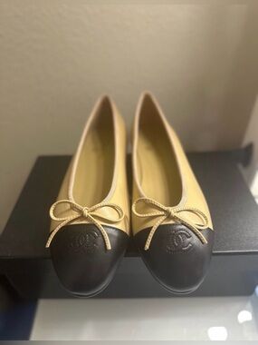Chanel ballet flats in beige lambskin body & black cap toe with CC logo.